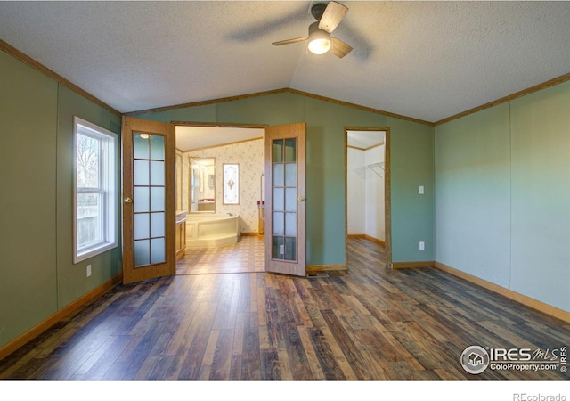 spare room featuring vaulted ceiling, dark wood-type flooring, ornamental molding, and french doors