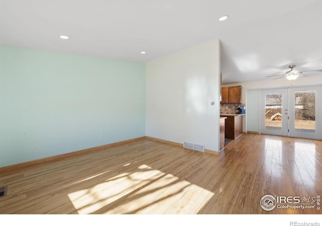 unfurnished living room featuring french doors, ceiling fan, and light wood-type flooring