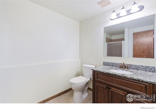 bathroom with tile patterned flooring, vanity, toilet, and walk in shower