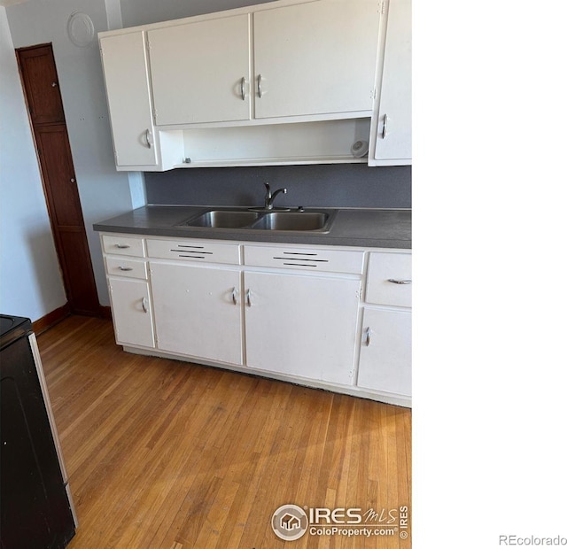 kitchen featuring sink, electric range, white cabinets, and light wood-type flooring