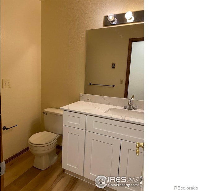 bathroom with vanity, toilet, and hardwood / wood-style floors