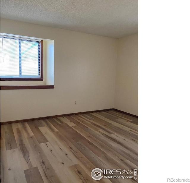 spare room featuring light hardwood / wood-style floors and a textured ceiling