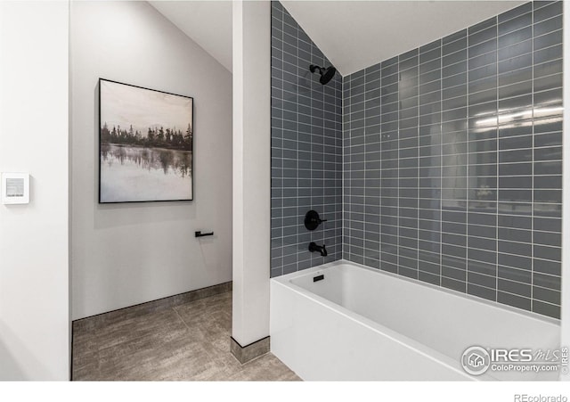 bathroom featuring lofted ceiling and tiled shower / bath combo