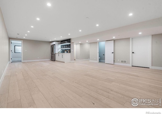 unfurnished living room with indoor bar and light wood-type flooring