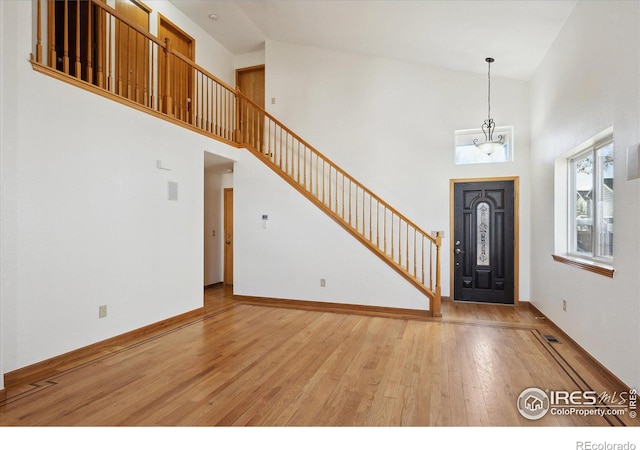 entryway with a towering ceiling, visible vents, stairway, and hardwood / wood-style floors