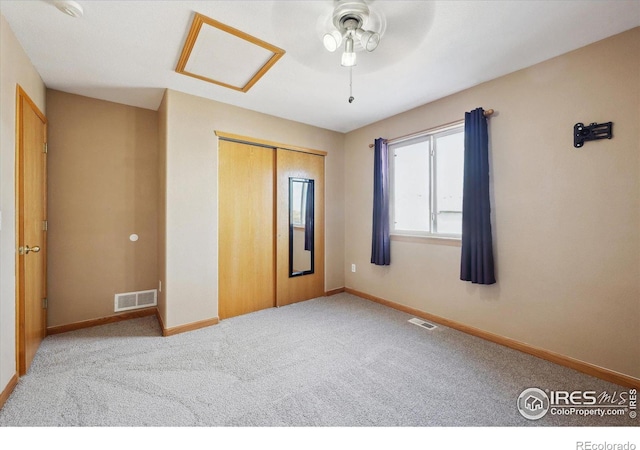 unfurnished bedroom with attic access, a closet, visible vents, and carpet floors