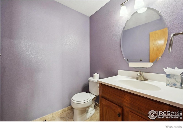 half bath featuring a textured wall, vanity, toilet, and tile patterned floors