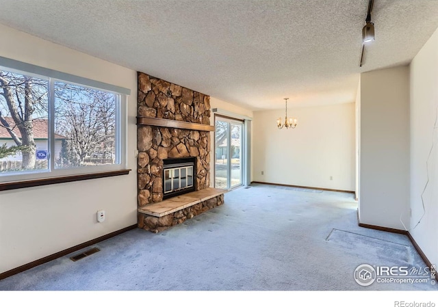 unfurnished living room with a notable chandelier, a fireplace, a textured ceiling, and carpet