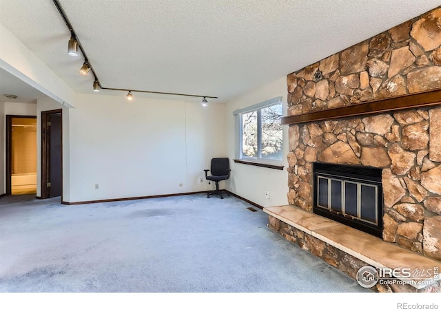 unfurnished living room featuring a fireplace, track lighting, a textured ceiling, and carpet