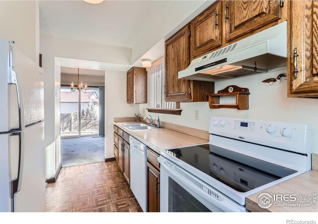 kitchen with sink, dark parquet floors, a notable chandelier, pendant lighting, and white appliances