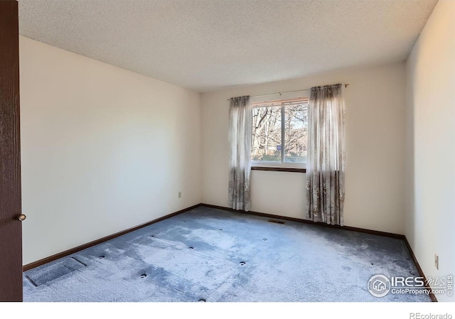 carpeted empty room with a textured ceiling