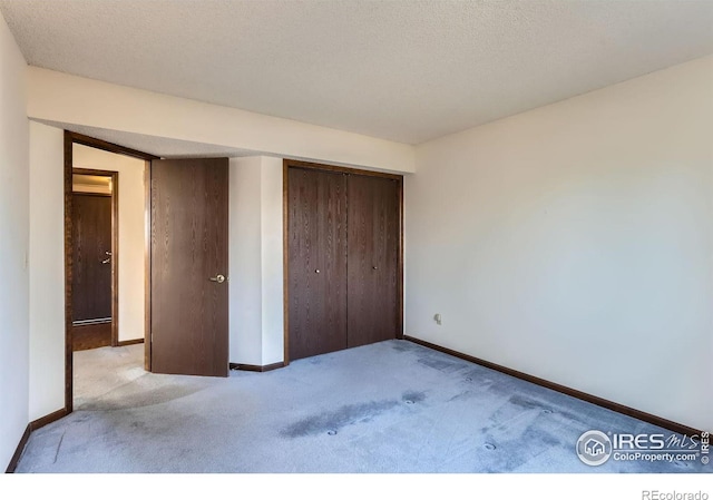 unfurnished bedroom featuring light colored carpet, a textured ceiling, and a closet