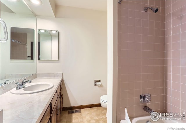 full bathroom with tiled shower / bath combo, vanity, and toilet