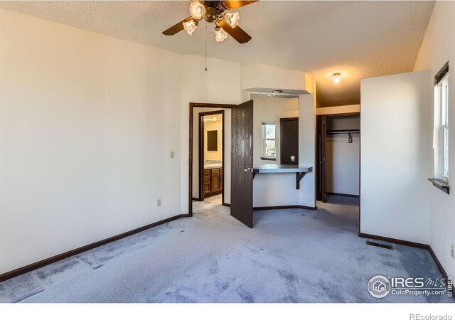 interior space with ceiling fan, light carpet, and a textured ceiling