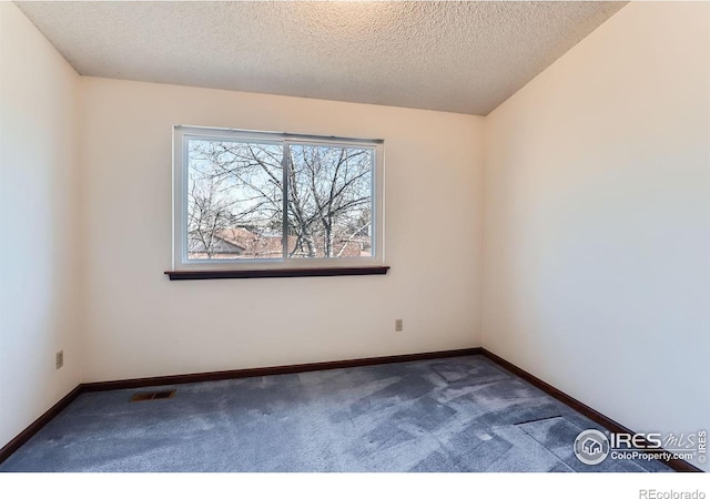 spare room with dark carpet and a textured ceiling