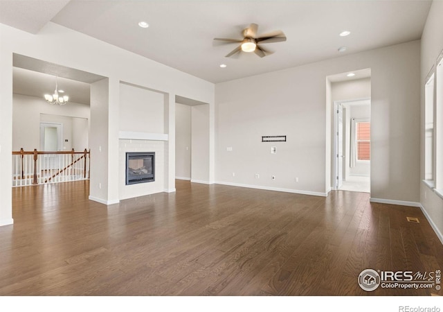 979 Stagecoach Dr, Lafayette, CO 80026 - unfurnished living room featuring dark wood-style flooring, ceiling fan, baseboards, a chandelier, and a glass covered fireplace