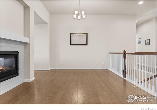 979 Stagecoach Dr, Lafayette, CO 80026 - unfurnished living room with wood finished floors, a multi sided fireplace, recessed lighting, baseboards, and a chandelier
