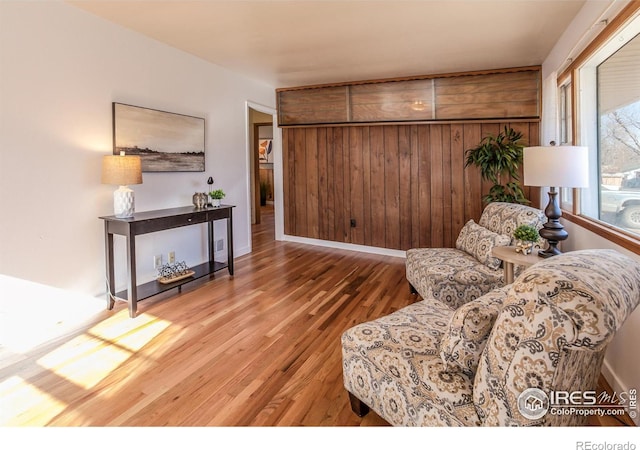 sitting room featuring wood-type flooring and wooden walls