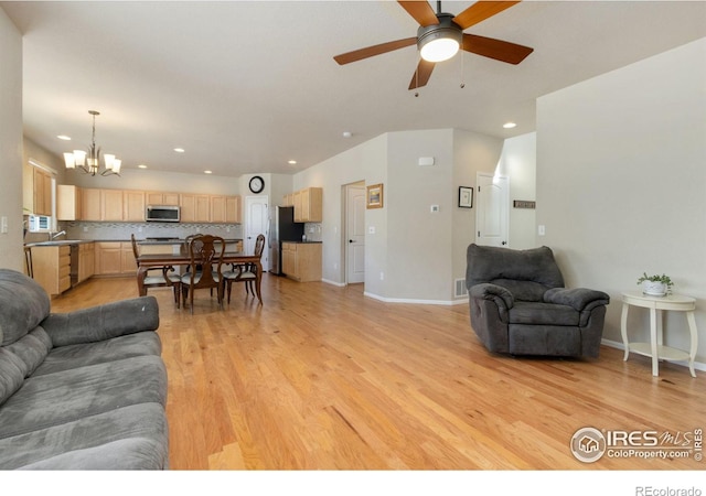 living room with ceiling fan with notable chandelier and light wood-type flooring