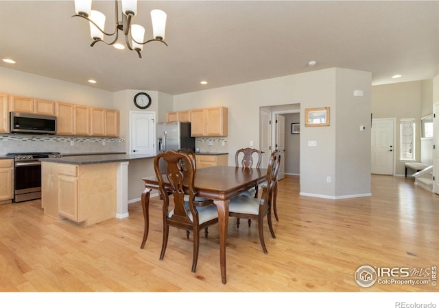 dining space with light hardwood / wood-style floors and a notable chandelier