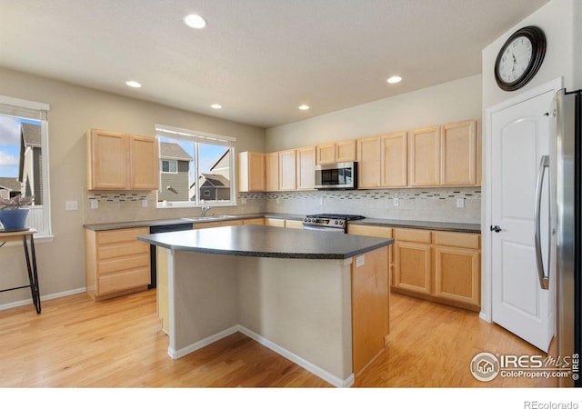 kitchen featuring a kitchen island, appliances with stainless steel finishes, sink, decorative backsplash, and light wood-type flooring