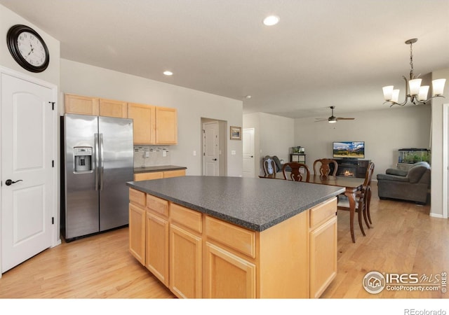 kitchen featuring light brown cabinetry, hanging light fixtures, stainless steel fridge, a kitchen island, and light hardwood / wood-style floors