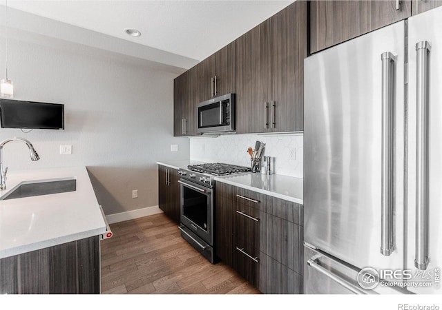 kitchen with tasteful backsplash, dark brown cabinetry, high quality appliances, and sink