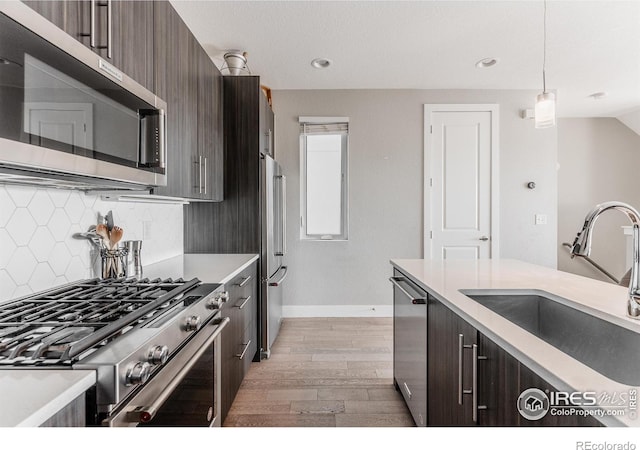 kitchen with sink, decorative light fixtures, dark brown cabinets, and appliances with stainless steel finishes