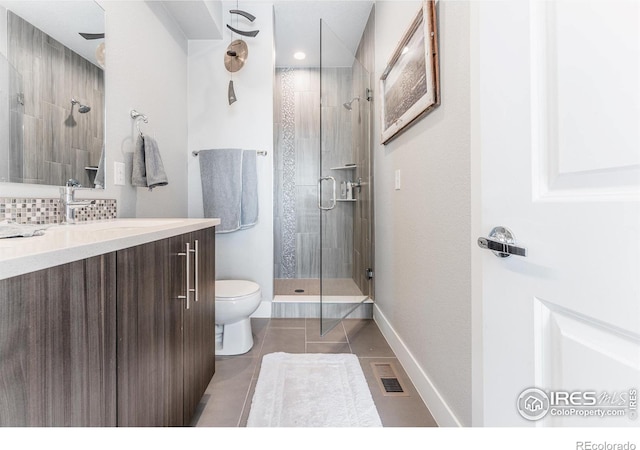 bathroom with tile patterned flooring, vanity, toilet, and walk in shower