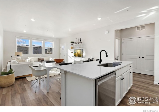 kitchen featuring sink, dishwasher, an island with sink, hardwood / wood-style floors, and white cabinets