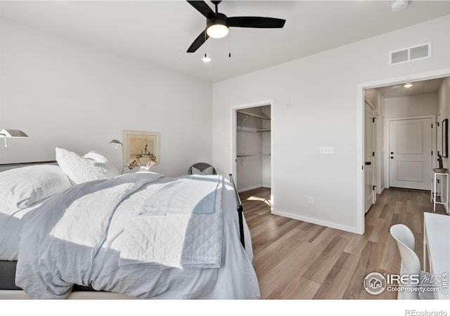 bedroom featuring ceiling fan, a spacious closet, light hardwood / wood-style floors, and a closet