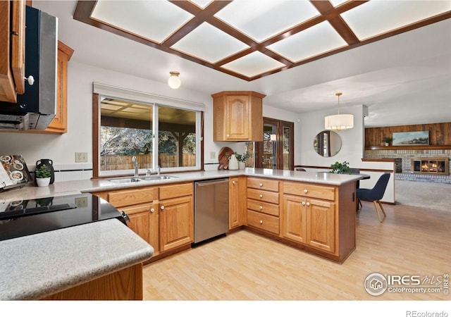 kitchen featuring sink, hanging light fixtures, a fireplace, stainless steel dishwasher, and kitchen peninsula