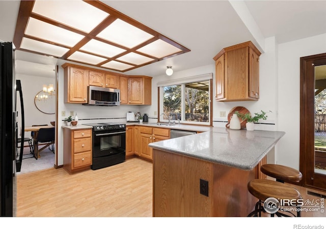 kitchen with sink, light hardwood / wood-style flooring, kitchen peninsula, a notable chandelier, and black appliances