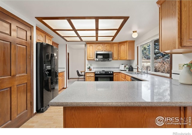 kitchen featuring light hardwood / wood-style flooring, sink, kitchen peninsula, and black appliances