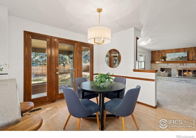 dining area with light wood-type flooring and a fireplace