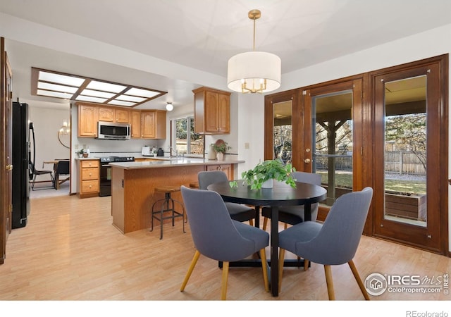 dining space featuring sink, light hardwood / wood-style floors, and a chandelier