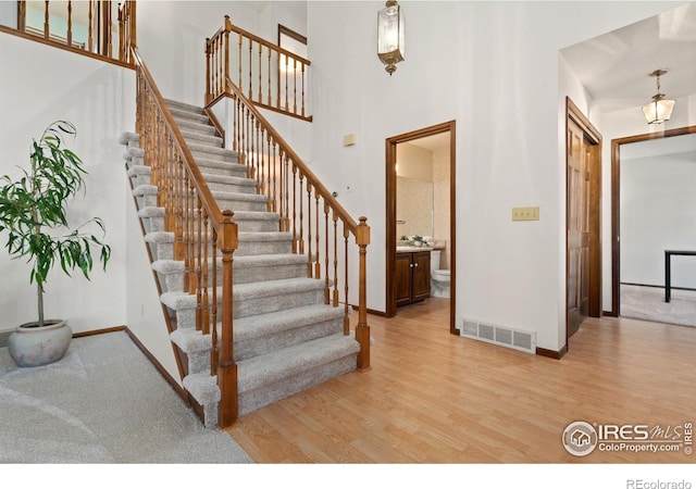 stairs featuring hardwood / wood-style flooring and a towering ceiling