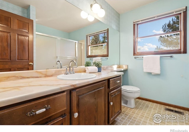 bathroom featuring vanity, toilet, a wealth of natural light, and a shower with shower door