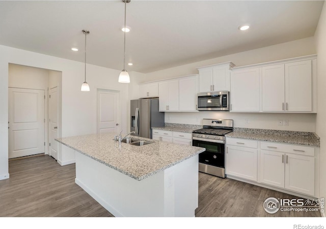 kitchen with an island with sink, sink, white cabinets, hanging light fixtures, and stainless steel appliances