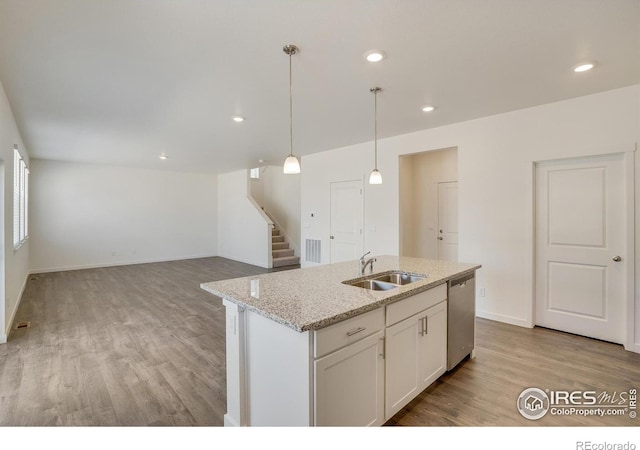 kitchen with pendant lighting, sink, light stone countertops, white cabinets, and stainless steel dishwasher