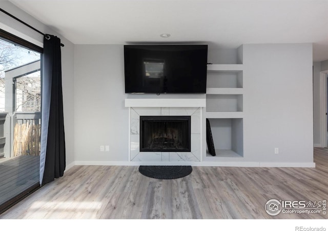 unfurnished living room with a tiled fireplace and light hardwood / wood-style floors