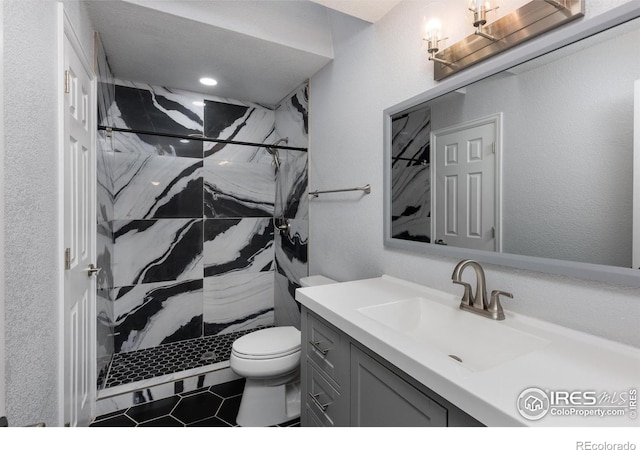 bathroom featuring tiled shower, vanity, and toilet