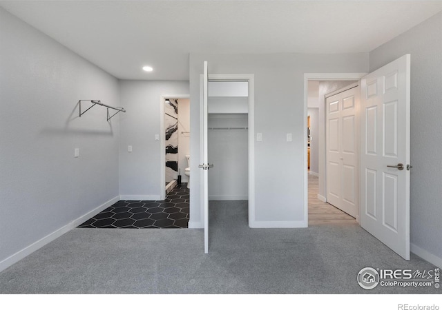 interior space featuring a walk in closet, a closet, and dark colored carpet