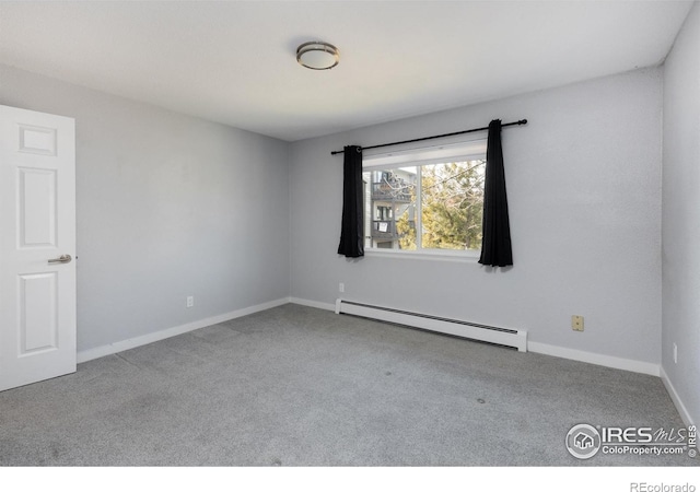 carpeted spare room with a baseboard heating unit