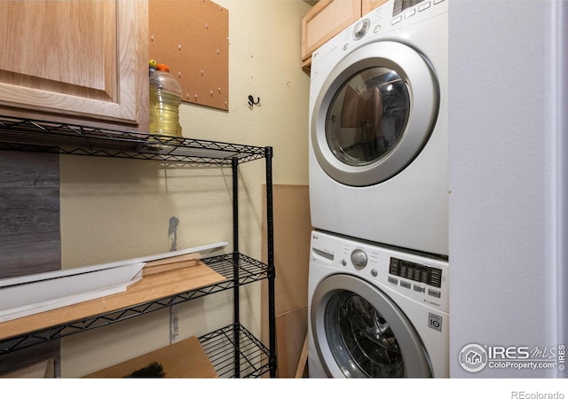 laundry room featuring stacked washer and dryer and cabinets