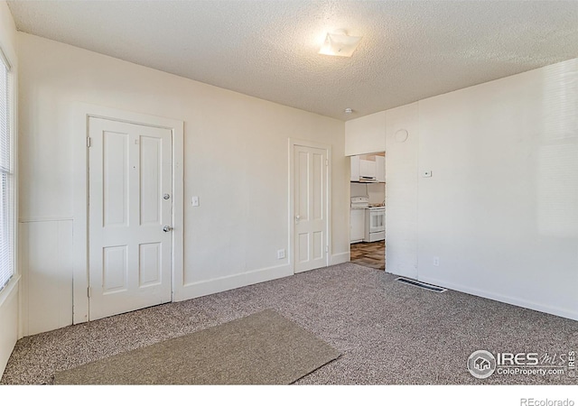 unfurnished room featuring dark carpet and a textured ceiling