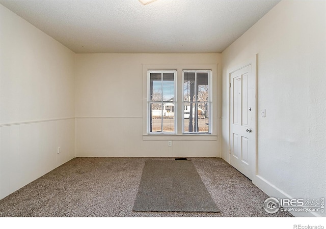 empty room with carpet flooring and a textured ceiling