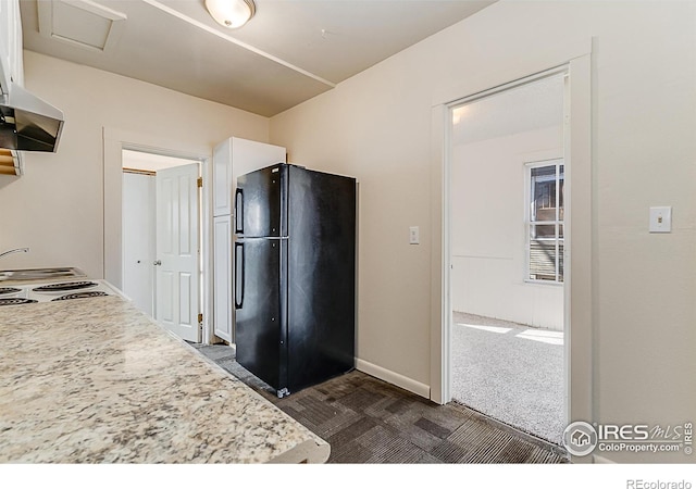 kitchen featuring dark colored carpet, black fridge, white cabinets, and extractor fan