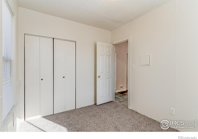 unfurnished bedroom featuring carpet, a textured ceiling, and a closet