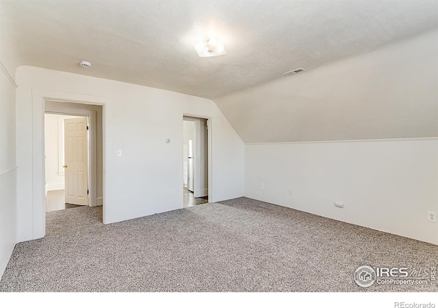 bonus room with carpet floors, a textured ceiling, and vaulted ceiling